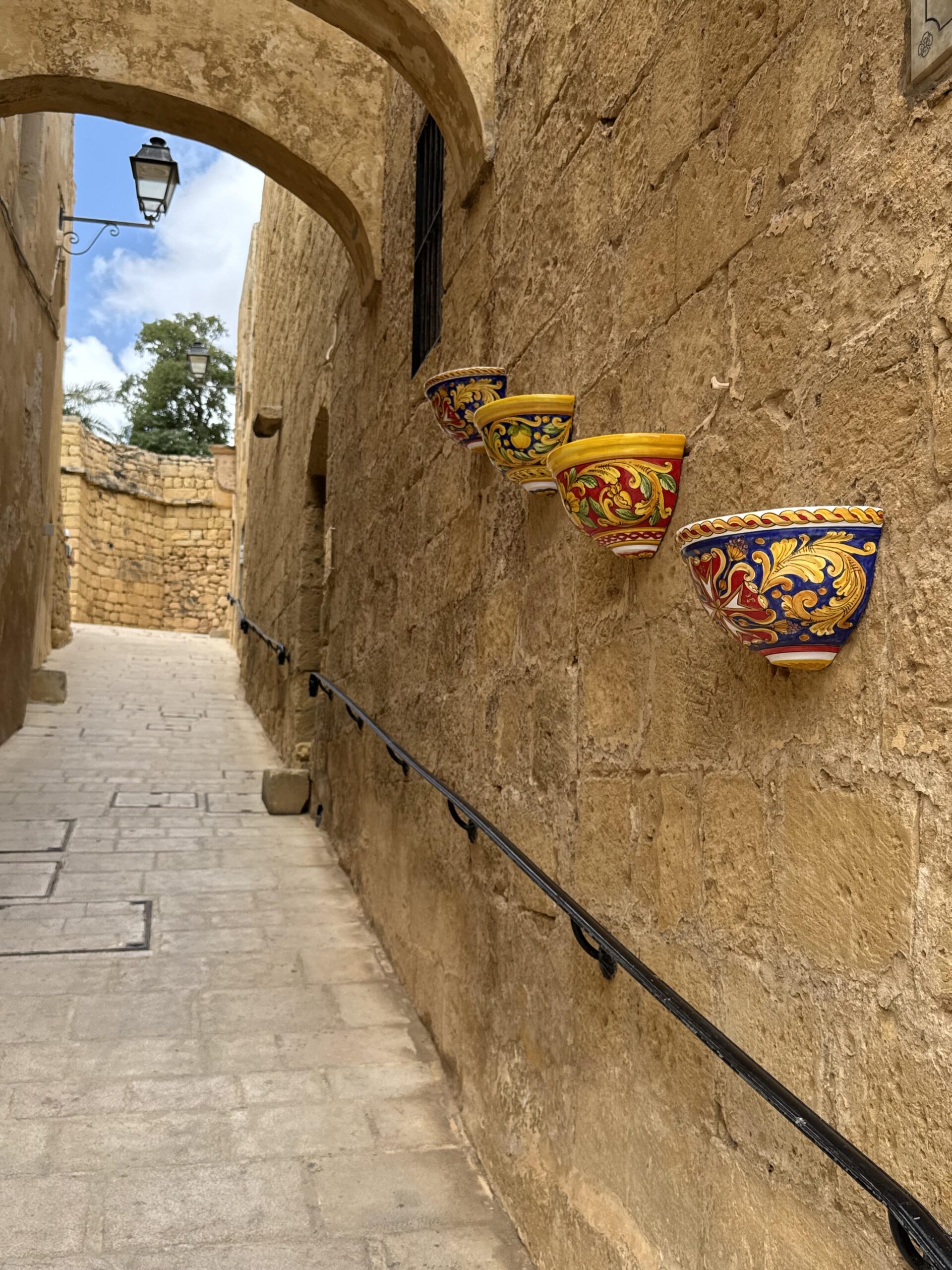 Hand-painted colorful ceramic pots displayed against a textured historic stone wall.