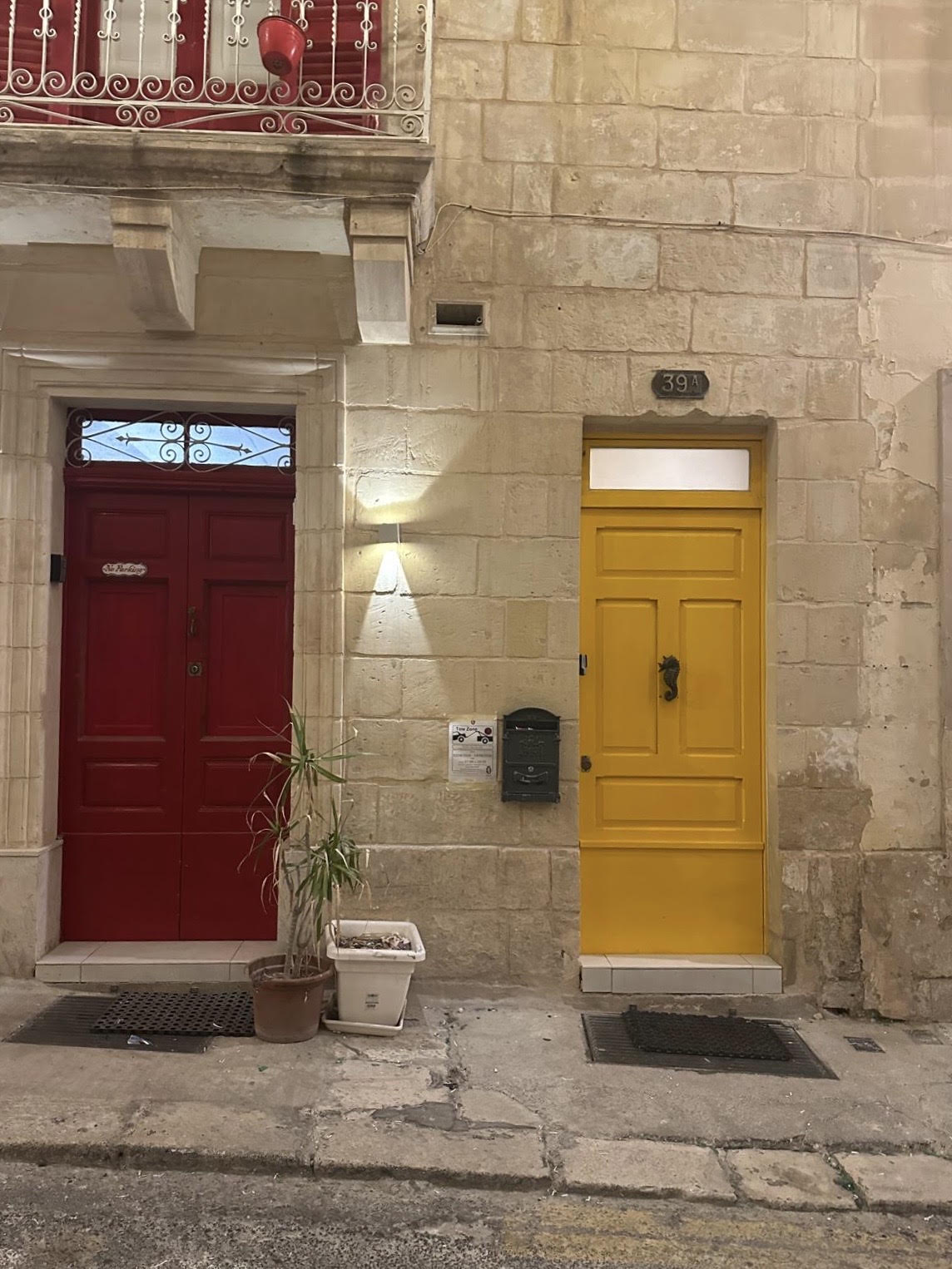 Red and yellow doors adding bold color and character to a traditional limestone facade.