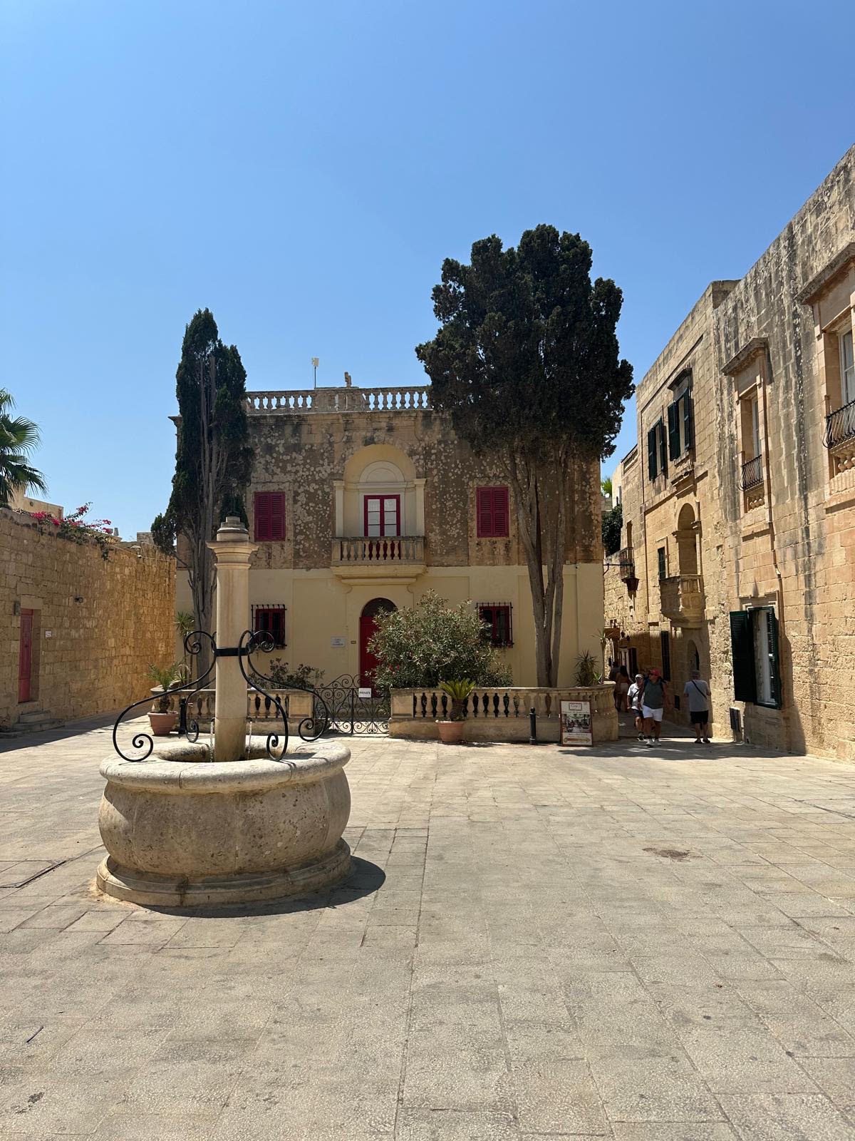 Historic limestone courtyard with a traditional stone well and Mediterranean architectural details.